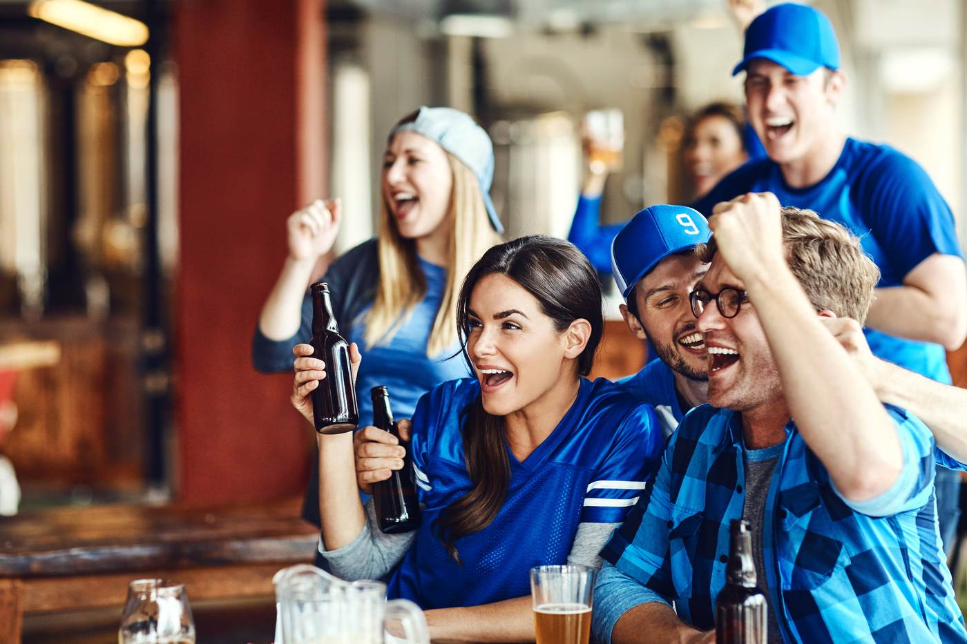 Fans cheering with drinks at the bar during a game