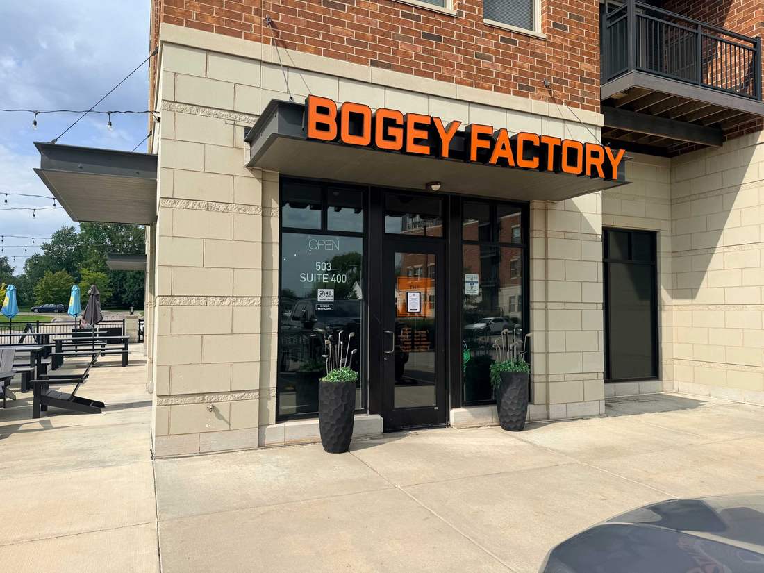 Back entrance at 503 Suite 400 with golf club planters, patio seating, and string lights