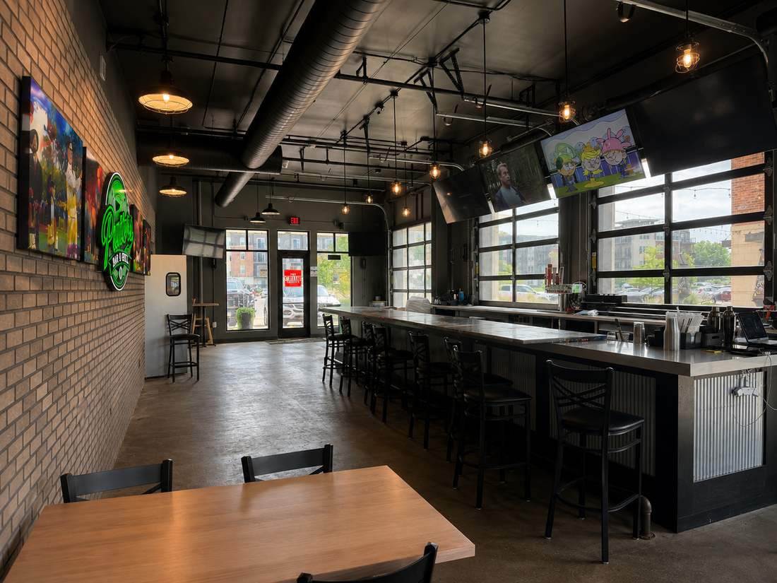 Bar seating with TVs overhead and natural light from the garage-door windows