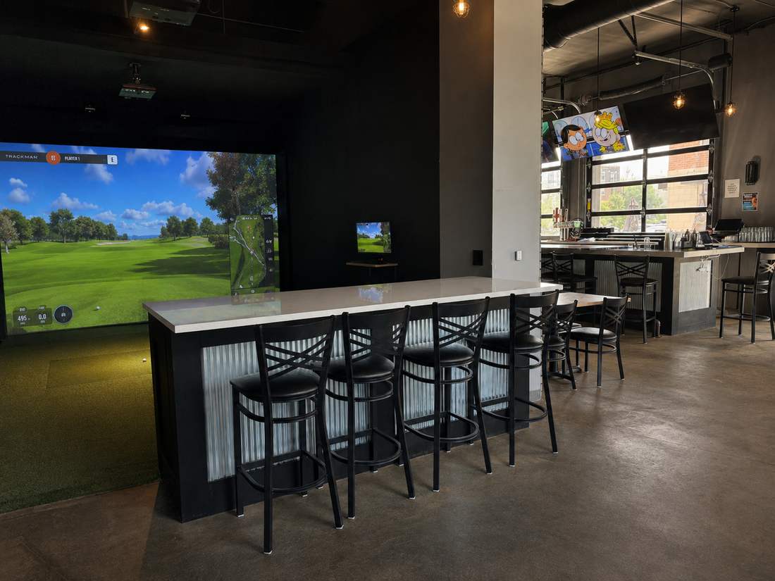 TrackMan golf simulator bay with bar-top seating at Putters