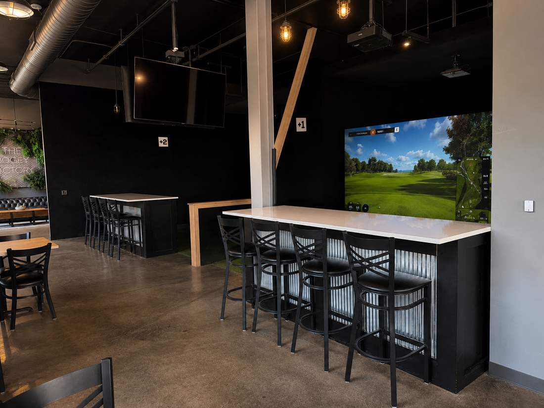 Golf simulator screen showing a fairway, with bay seating in the dining room